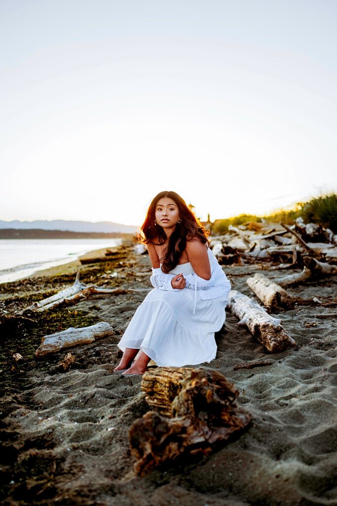 Seattle senior girl leaning on the lighthouse at Discovery Park in Seattle Washington, wearing a white dress, Seattle Summer Senior Portraits